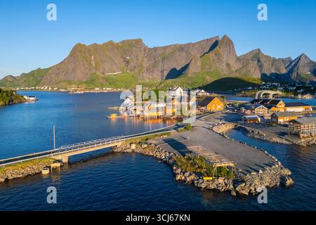 Vista aerea dell'isola di Sakrisøya e della baia di Reine verso Reinebringen in estate all'alba durante il sole di mezzanotte. Isole Lofoten, Norvegia. Foto Stock
