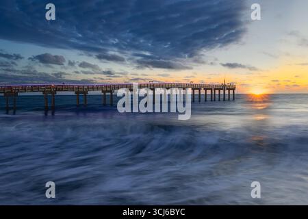 St Augustine Pier Break - le onde si schiantano contro il lungo molo che si estende nell'oceano. Foto Stock