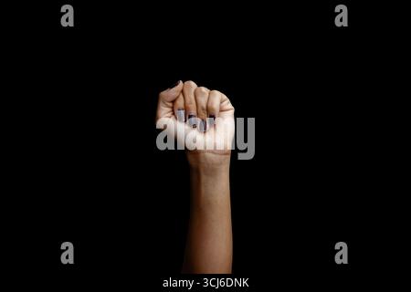 Un potente pugno con il clacchio femminile è stato innalzato, simboleggiando forza, protesta, vittoria e solidarietà. Isolato su sfondo nero. Foto Stock