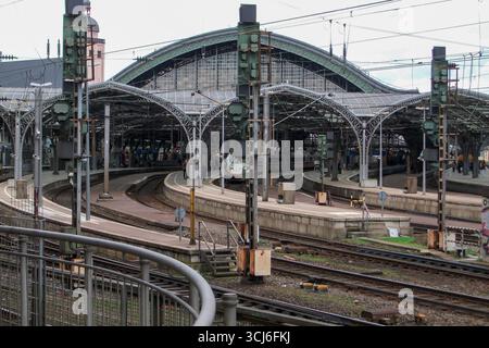 Stazione ferroviaria storica con piattaforme curve, struttura del tetto in acciaio e treno ICE ad alta velocità in arrivo a Colonia, Germania. Foto Stock