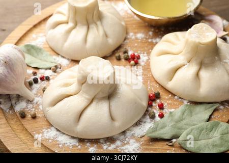 Kinkalis crudi (gnocchi) con grani di pepe, farina e foglie di alloro su un tavolo di legno, primo piano Foto Stock
