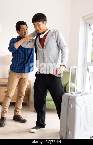 Gli amici si preparano per il viaggio, fanno valigia e sorridono in salotto Foto Stock