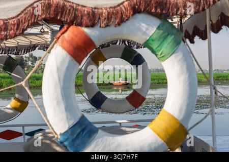 Vista astratta del tradizionale pescatore beduino egiziano in barca a remi sul fiume Nilo che pesca in riva al fiume attraverso boe anulare Foto Stock