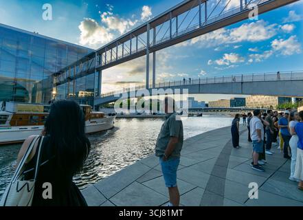 Gruppo di turisti vicino alla Sprea che guardano un passaggio in barca sotto Marie-Elisabeth-Lüders-Steg in una calda serata estiva. Foto Stock