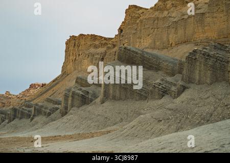 Uno scatto grandangolare e basso cattura le spettacolari formazioni geologiche di un aspro paesaggio desertico. A dominare lo sfondo c'è un torreggiante, marrone chiaro Foto Stock