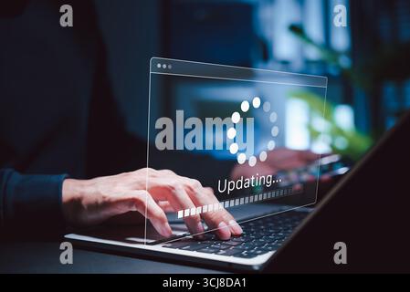 Informazioni sull'aggiornamento software e sull'aggiornamento del sistema. Persona che tiene il telefono mentre utilizza un computer portatile con interfaccia di avanzamento dell'aggiornamento software e sicurezza, tecnologia Foto Stock