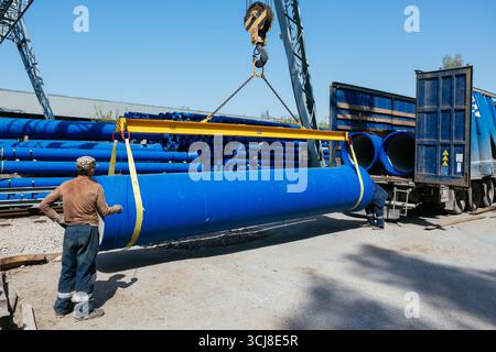 Caricamento del tubo in ghisa nel camion per il trasporto con carroponte. Foto Stock