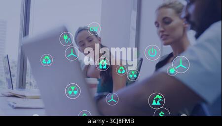 Discutete dei colleghi che lavorano all'energia che si appoggiano al computer portatile e al caffè nella sala riunioni, con icone fluttuanti Foto Stock