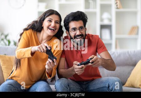 Coppia indiana allegra divertirsi a casa, giocare insieme ai videogiochi Foto Stock