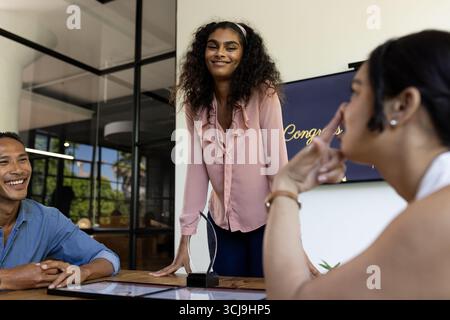 Donna d'affari sorridente che conduce riunioni con colleghi in un ambiente moderno Foto Stock
