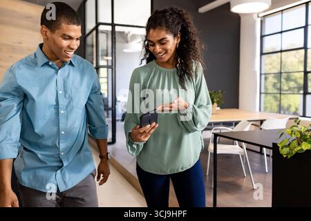 Camminare attraverso un ufficio moderno, i colleghi discutono di un progetto, sorridono e si impegnano Foto Stock
