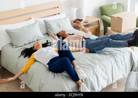 Rilassatevi a casa, due donne sdraiate a letto dopo una giornata trascorsa, si sentono sfiniti Foto Stock