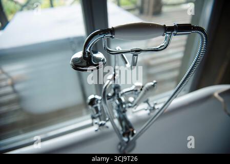 Primo piano di un rubinetto per vasca da bagno cromato in stile vintage con soffione portatile. Foto Stock