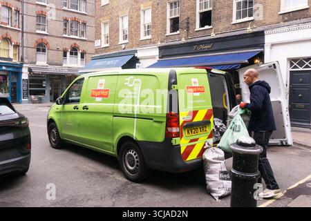 Un veicolo elettrico a emissioni zero Royal mail viene caricato sotto la pioggia nel Shepherd Market, Londra. Foto Stock
