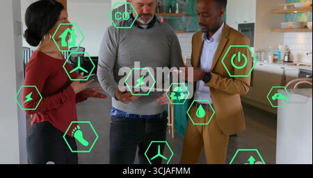 Visualizzazione di tablet e smartphone, tre professionisti che analizzano le icone verdi della realtà aumentata nella cucina domestica Foto Stock
