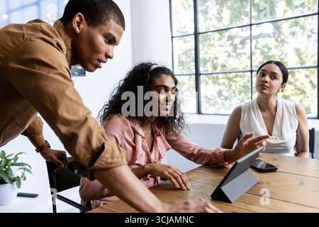 Collaborare in un ufficio moderno, discutere i dettagli del progetto utilizzando un tablet Foto Stock