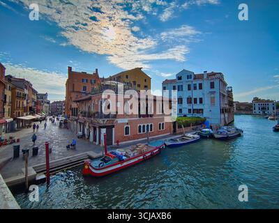 Una foto grandangolare dell'iconico Canal grande di Venezia in una giornata di sole, con palazzi storici e altre imbarcazioni visibili lungo il vivace corso d'acqua. Foto Stock