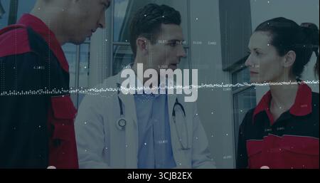 Discutere di medici che condividono i dati vitali con gli EMT nei corridoi con pannelli di vetro, stetoscopio e uniformi Foto Stock