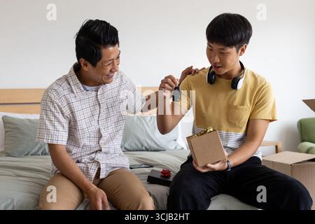 Padre e figlio condividono un momento di gioia con la chiave dell'auto a letto Foto Stock