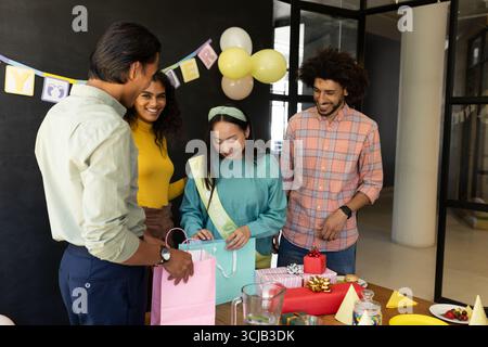 In ufficio, diversi colleghi scambiano regali e celebrano l'atmosfera festosa Foto Stock