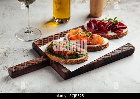 Tre panini gourmet aperti su tavola di legno Foto Stock