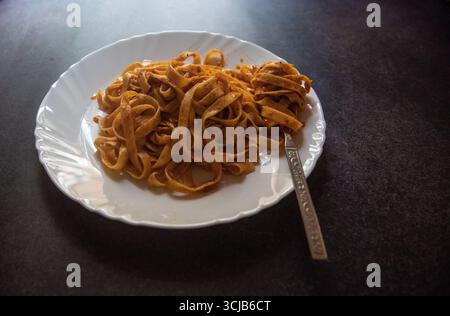 Pasta fettuccine cotta servita su un piatto bianco. Foto Stock