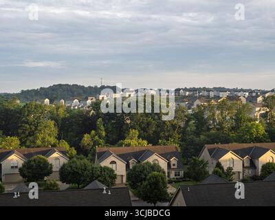 Una vista idilliaca delle case suburbane annidate in un paesaggio collinare sotto un cielo nuvoloso e luminoso in Pennsylvania, Stati Uniti. Foto Stock
