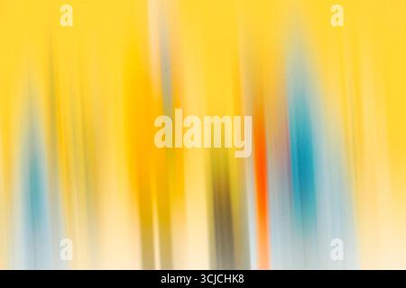 Un'immagine astratta caratterizzata da una vivace sfocatura in movimento con colori giallo, blu e sfumature di rosso che creano una texture dinamica e artistica. Perfetto per il moderno Foto Stock