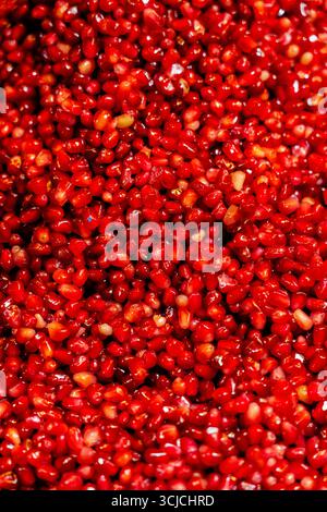 Una vista ravvicinata dei vibranti semi di melograno rosso, che simboleggiano la salute e l'abbondanza. Questi semi succosi sono un frutto popolare nelle culture mediorientali A. Foto Stock