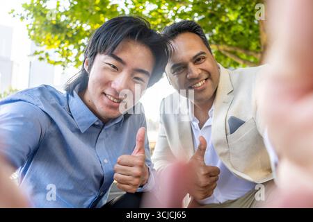Due partner aziendali sorridenti si danno il pollice mentre fanno un selfie all'aperto a Melbourne. L'immagine trasmette il successo, il lavoro di squadra e un business positivo Foto Stock