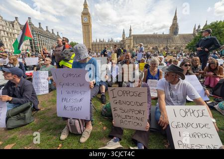 Londra, Regno Unito. 6 settembre 2025.i manifestanti si riuniscono fuori dal Palazzo di Westminster a Londra, con il Big Ben visibile sullo sfondo, per protestare contro il genocidio ed esprimere solidarietà alla Palestina. I manifestanti sono seduti sull'erba e recano cartelli che leggono: Io SONO CONTRARIO AL GENOCIDIO e SOSTENGO L'AZIONE DELLA PALESTINA. Una bandiera palestinese è visibile tra la folla. La protesta evidenzia l'attivismo pubblico sui diritti umani internazionali e il conflitto geopolitico. Penelope Barritt/Alamy Live News Foto Stock