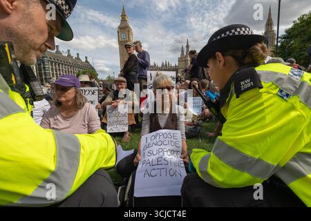 Londra, Regno Unito. 6 settembre 2025. I manifestanti si riuniscono sull'erba fuori dal Palazzo di Westminster a Londra, tenendo dei cartelli a sostegno della Palestina e opponendosi al genocidio. La protesta presenta partecipanti seduti, cartelli visibili con messaggi politici. Agenti di polizia in giacche ad alta visibilità. Difendere la protesta delle nostre giurie per la proscrizione dell’azione contro la Palestina, con oltre 1000 persone che si impegnano a tenere dei segnali contro il divieto dei laburisti e a dimostrare sostegno al gruppo proscritto. Penelope Barritt/Alamy Live News Foto Stock