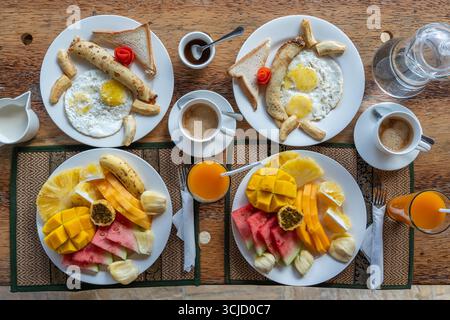 Colazione tropicale a base di frutta, caffè e uova strapazzate e pancake alla banana per due sulla spiaggia vicino al mare nel ristorante dell'hotel, isola di Zanzibar, Tanzania Foto Stock