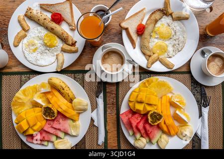 Colazione tropicale a base di frutta, caffè e uova strapazzate e pancake alla banana per due sulla spiaggia vicino al mare nel ristorante dell'hotel, isola di Zanzibar, Tanzania Foto Stock