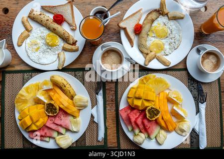Colazione tropicale a base di frutta, caffè e uova strapazzate e pancake alla banana per due sulla spiaggia vicino al mare nel ristorante dell'hotel, isola di Zanzibar, Tanzania Foto Stock