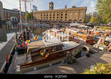 Londra, Regno Unito. 6 settembre 2025. Una vivace marina con barche in legno d'epoca adornate con bandiere celebrative, ormeggiate accanto a uno storico magazzino di mattoni con una torre dell'orologio. L'evento offre attività sociali, apprezzamento del patrimonio culturale e svago sul lungomare. St Katharine Docks Classic Boat Festival con oltre 60 barche classiche e d'epoca, tra cui le piccole navi di Dunkirk in mostra al pubblico. Penelope Barritt/Alamy Live News Foto Stock