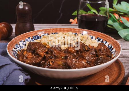 Stufato di manzo con gnocchi di spaetzle condito con paprika e servito con vino rosso, un piatto tradizionale ungherese Foto Stock