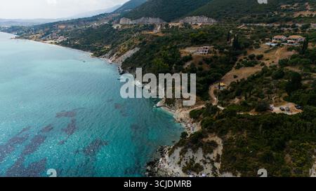 Vista aerea della costa di Zante Grecia con scogliere rocciose case turchesi sul Mar Ionio e un paesaggio verde che si estende lungo la riva Foto Stock