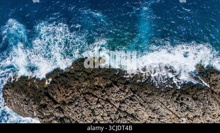 Vista aerea estiva di Zante, Grecia, aspro promontorio roccioso con onde che si infrangono contro le scogliere circondate dal Mar Ionio scuro e turchese Foto Stock