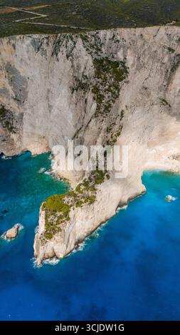 Zante Grecia, Spiaggia Bianca, vista aerea delle scogliere calcaree che torreggiano sul turchese Mar Ionio con una piccola baia rocciosa che crea un paesaggio epico Foto Stock