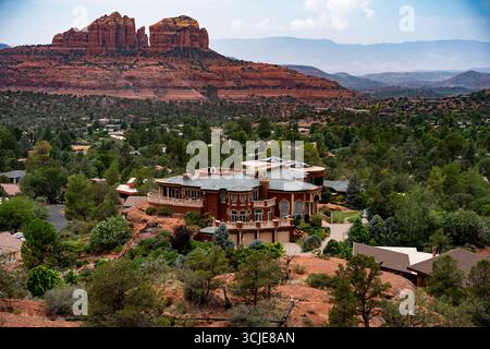 Una vista panoramica ad alto angolo cattura una magnifica e lussuosa tenuta annidata tra lussureggianti alberi verdi e la variegata vegetazione del deserto. L'estenuante redd Foto Stock