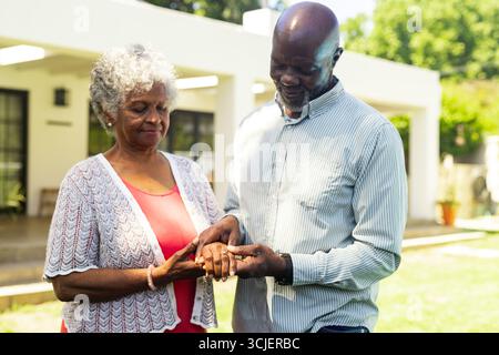 Coppia di anziani che si scambiano anelli all'aperto, celebrando l'amore e l'impegno insieme Foto Stock