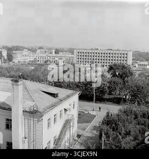 Una vista panoramica della piazza centrale della Rivoluzione d'ottobre (ora piazza Soborna) nella città di Slavyansk durante la seconda metà degli anni '1970, che mostra il cuore di una città sovietica nell'era della stagnazione: L'edificio monumentale del comitato esecutivo della città, il monumento Lenin e un giardino pubblico ben tenuto, catturato da un punto alto in un tranquillo giorno feriale, che serve da preziosa testimonianza della vita pacifica Donbas Foto Stock