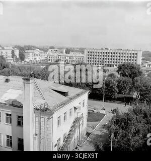 Una vista panoramica della piazza centrale della Rivoluzione d'ottobre (ora piazza Soborna) nella città di Slavyansk durante la seconda metà degli anni '1970, che mostra il cuore di una città sovietica nell'era della stagnazione: L'edificio monumentale del comitato esecutivo della città, il monumento Lenin e un giardino pubblico ben tenuto, catturato da un punto alto in un tranquillo giorno feriale, che serve da preziosa testimonianza della vita pacifica Donbas Foto Stock