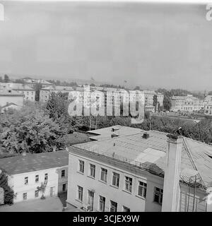 Una vista panoramica della piazza centrale della Rivoluzione d'ottobre (ora piazza Soborna) nella città di Slavyansk durante la seconda metà degli anni '1970, che mostra il cuore di una città sovietica nell'era della stagnazione: L'edificio monumentale del comitato esecutivo della città, il monumento Lenin e un giardino pubblico ben tenuto, catturato da un punto alto in un tranquillo giorno feriale, che serve da preziosa testimonianza della vita pacifica Donbas Foto Stock
