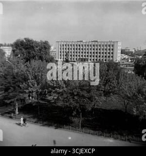 Una vista panoramica della piazza centrale della Rivoluzione d'ottobre (ora piazza Soborna) nella città di Slavyansk durante la seconda metà degli anni '1970, che mostra il cuore di una città sovietica nell'era della stagnazione: L'edificio monumentale del comitato esecutivo della città, il monumento Lenin e un giardino pubblico ben tenuto, catturato da un punto alto in un tranquillo giorno feriale, che serve da preziosa testimonianza della vita pacifica Donbas Foto Stock