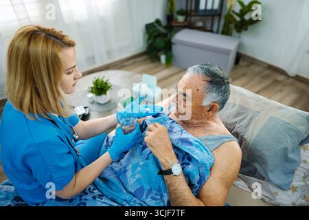 Assistente che assiste gli anziani in un ambiente accogliente Foto Stock
