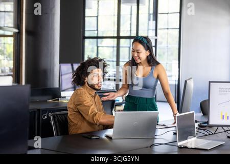 Colleghi che collaborano al progetto utilizzando laptop in un ufficio moderno Foto Stock