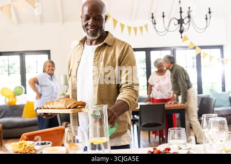 Serve pane alla riunione di famiglia, un afroamericano sorride durante la festa Foto Stock