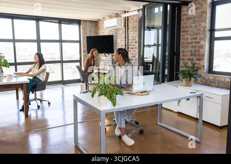 Colleghi in un ufficio moderno che collaborano e discutono idee con i notebook Foto Stock